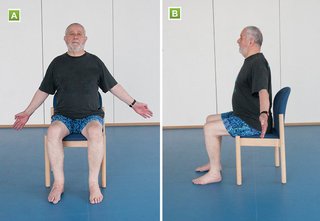 A seated man stretching his arms out on either side of his body, with his hands at hip level